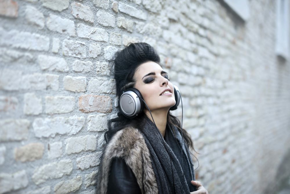 nieformalna mloda kobieta sluchajaca muzyki w poblizu grunge sciany